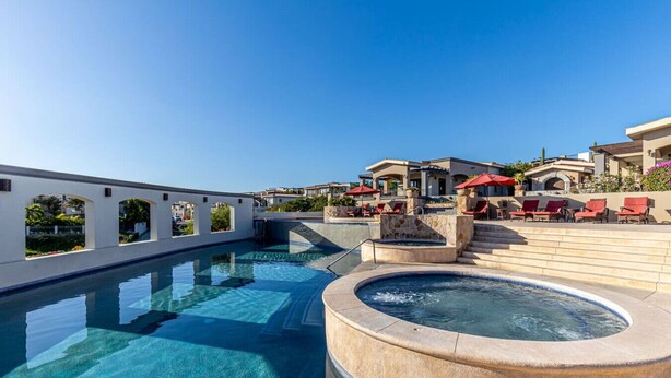 A rooftop pool area with clear blue water, a hot tub, and red lounge chairs. - Casa Rosas - Private pool (Cabo San Lucas)