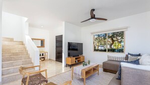 A modern living room with a staircase, a television, and a sofa. - Casa Rosas - Private pool (Cabo San Lucas)