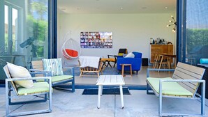 A modern living room with a large bookshelf, a hanging chair, and a dining area. - Quiet and peaceful retreat (La Quinta)