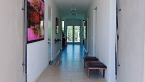 A modern hallway with a patterned rug, a bench, and a door with a framed picture. - Quiet and peaceful retreat (La Quinta)
