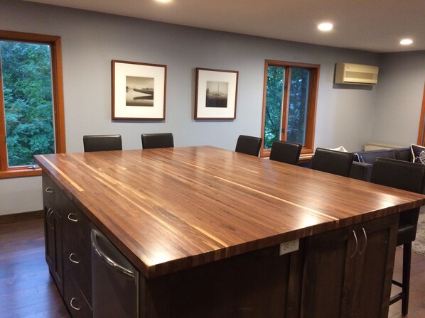A conference room with a large wooden table, black chairs, framed pictures on the wall, and a window with a view of trees.