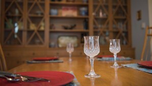 Een eettafel met twee glazen wijnglazen, rode borden en bestek.