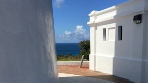 Un camino que lleva a un edificio blanco con vista al océano.