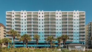 Un hôtel à plusieurs étages, doté de balcons, d’un toit plat et d’un espace de stationnement à l’avant.
