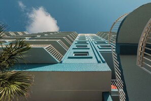 A modern building with a geometric facade, multiple balconies, and a clear sky.