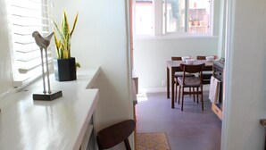 A kitchen with a white countertop, a dining area with a table and chairs, and a hallway leading to an open space. - Charming North Park house, with parking and new central Air.  (San Diego)