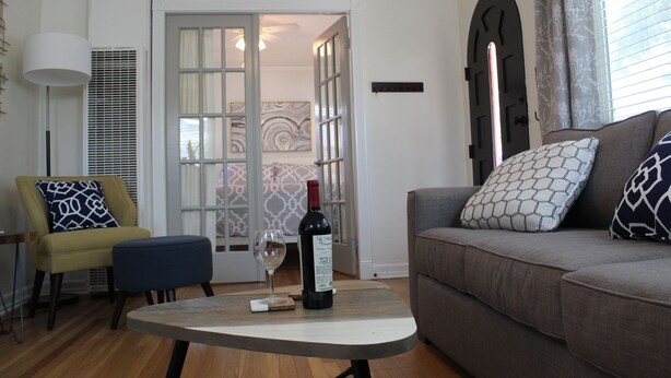 A living room with a sofa, a chair, a small table, and a wine bottle. - Charming North Park house, with parking and new central Air.  (San Diego)