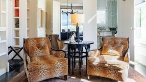 A room with two leopard print armchairs, a small round table, and a hanging light fixture.