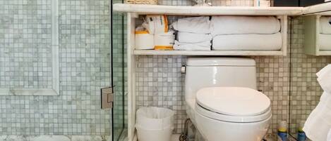 A bathroom with a toilet, shower, and tiled floor.