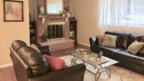 A living room with a fireplace, leather sofa, and a glass coffee table.