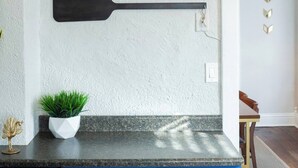 A kitchen with blue cabinets, a black countertop, and a wall-mounted paddle. - Charming Hideaway in Westport 15 (KCMO)