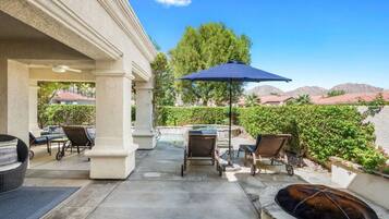 Un patio couvert avec des sièges d’extérieur, un foyer et une vue sur une chaîne de montagnes.