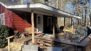 A wooden deck with outdoor furniture, a barbecue grill, and a covered porch area.
