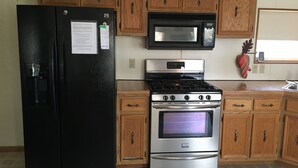 A kitchen with a black refrigerator, stainless steel stove, and microwave. - Cozy family & pet friendly lake home, great reviews & rates (Holcombe)