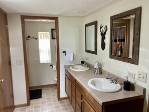 Un baño con dos lavamanos, armarios de madera, un espejo y una zona de ducha.