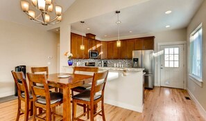 Enjoy cooking in this well-equipped kitchen with a central island, stainless steel appliances, and a dining area with a table and chairs.