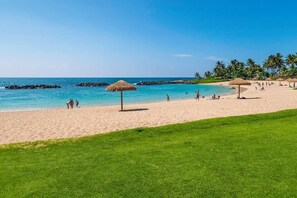 A beach with clear turquoise water, a sandy shore, and palm trees. - Beachfront Beach Villas at Ko Olina O-501 (Kapolei)