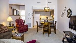 A living room with a red leather chair, a wooden dining table with chairs, a TV, and a lamp. - 🌄Resort Vacations at Fairfield Glade TN Spacious two bedroom Golf Villa (Fairfield Glade)