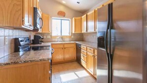 A kitchen with wooden cabinets, a stainless steel refrigerator, a microwave, and a stove. - The perfect place for outdoor recreation (Thayne)