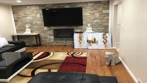 Relax in this stylish living room with a flat-screen TV above the fireplace, a black leather sofa, and a black ottoman.