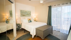 A bedroom with a bed, bedside tables, a mirror, a ceiling fan, and a window with curtains.