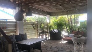 An outdoor patio with a stone floor, wicker furniture, and hanging light fixtures.
