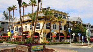A historic building with multiple balconies, palm trees, and outdoor seating areas.