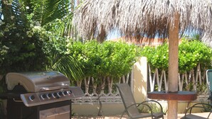 A patio area with a barbecue grill, two chairs, and a small table. - Superior 1-Bedroom Apartment - Aruba Cunucu Residence (Oranjestad)