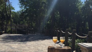 Un sendero pavimentado con un banco de madera y dos vasos de jugo de naranja sobre un tocón de árbol.