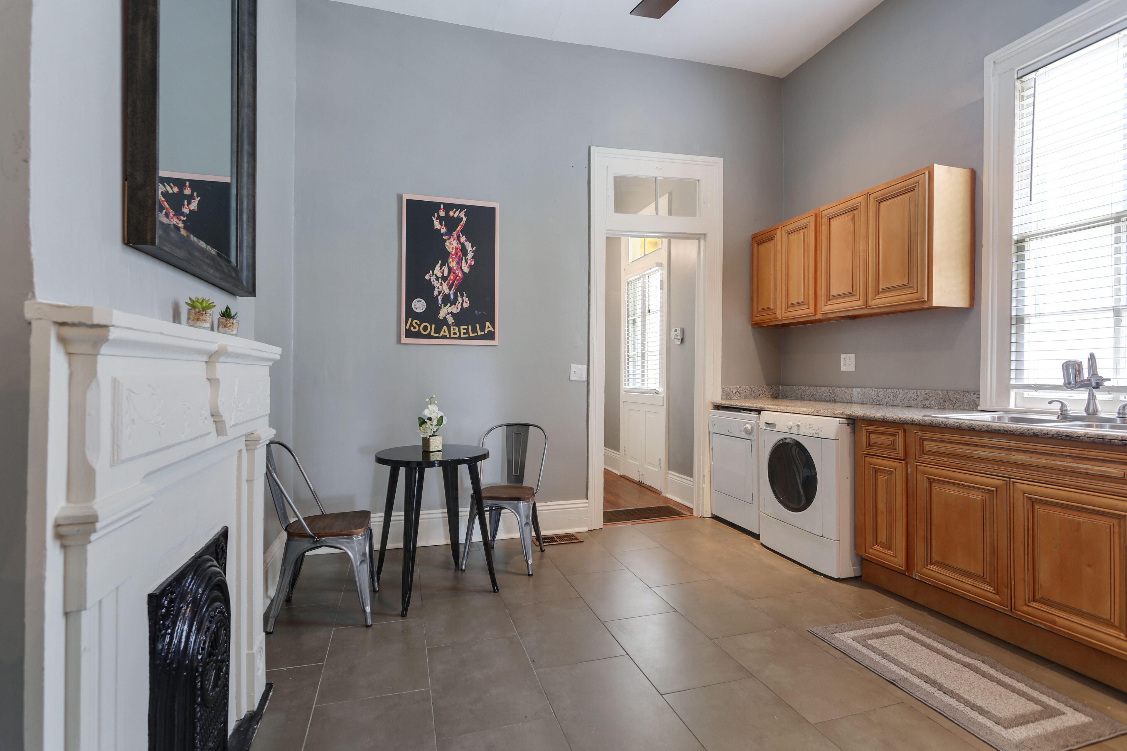 A kitchen with wooden cabinets, a washing machine, and a dining area with two chairs and a table.