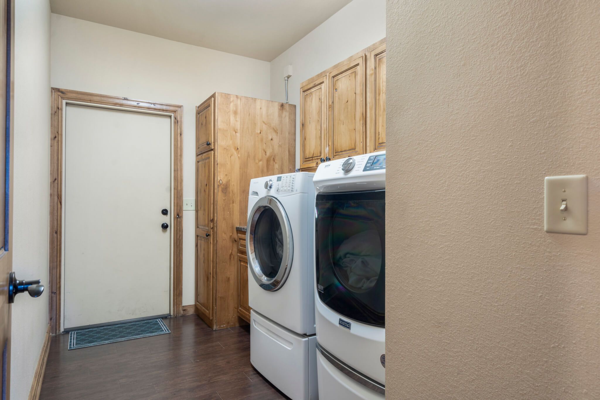 A laundry room with wooden cabinets and two stacked washers and dryers.