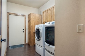 A laundry room with wooden cabinets and two stacked washers and dryers. - Lake View Retreat at CrossTimbers Marina (Sperry)
