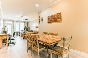 A dining area with a wooden table and chairs, a ceiling fan, and artwork on the wall.