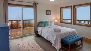 Ein Schlafzimmer mit Bett, Sitzbank, Deckenventilator und großen Fenstern.