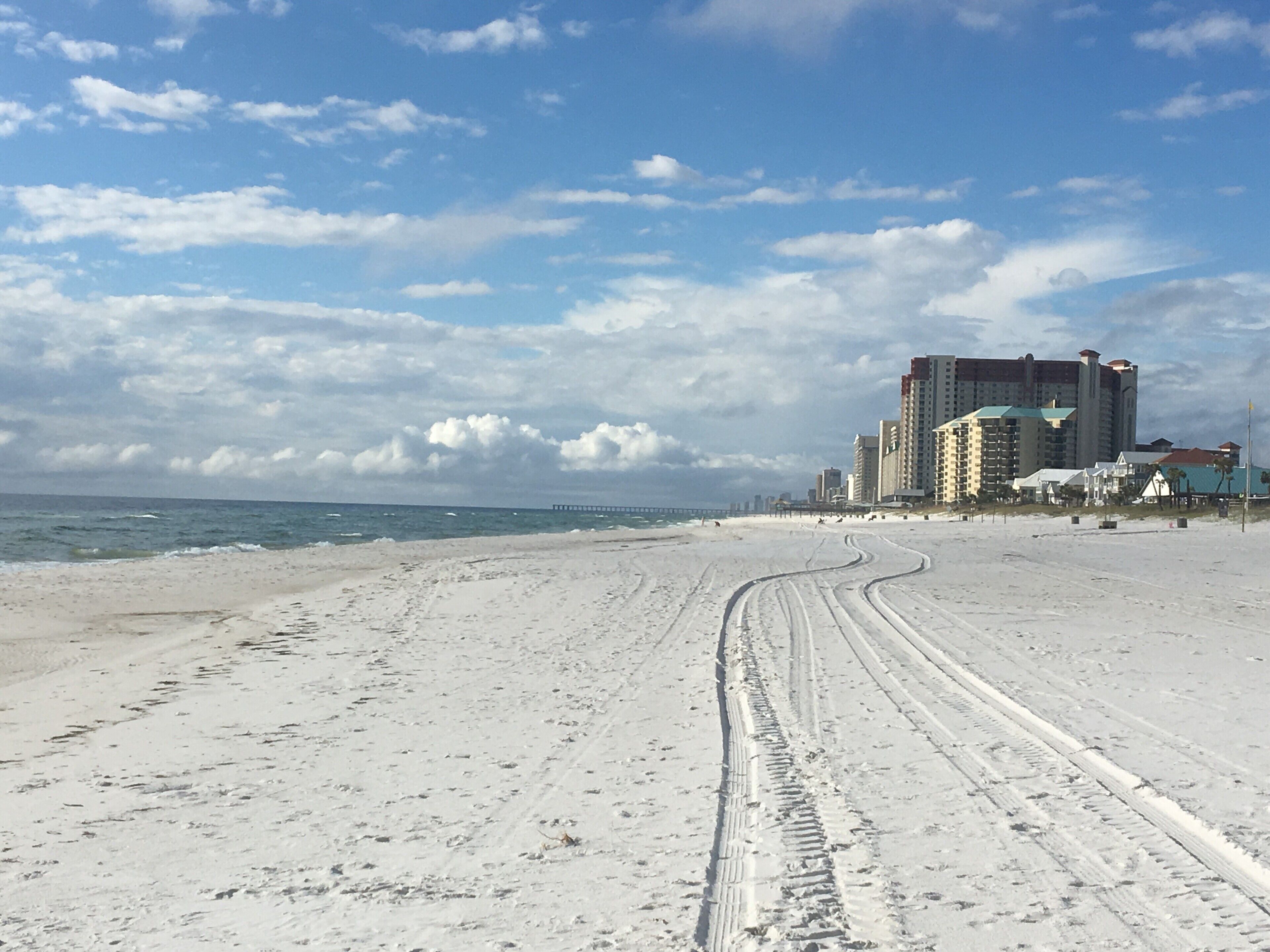 Une plage avec un ciel dégagé et un bâtiment en arrière-plan.