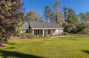 A single-story house with a gabled roof, a front porch, and a green door.