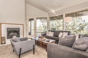 Cozy up by the fireplace in this stylish living room, featuring a comfortable sofa and large window with a view.
