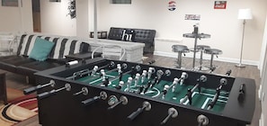 Una sala de estar con una mesa de fútbol, un sofá y una mesa de centro.