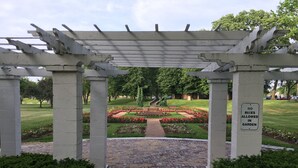 A garden entrance with a pergola, a sign prohibiting bikes, and a pathway leading to a flower bed. - Outrageous! Near Microsoft Mt Pleasant - Sleeps 18 (Kenosha)