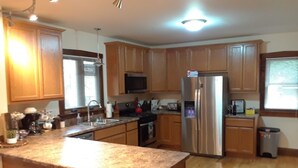 A kitchen with wooden cabinets, a stainless steel refrigerator, and a granite countertop. - Outrageous! Near Microsoft Mt Pleasant - Sleeps 18 (Kenosha)