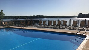 Ein Pool mit Liegestühlen und Blick auf ein Gewässer.