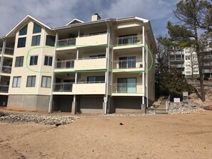 A multi-story residential building with balconies, a covered patio, and a visible roof vent.