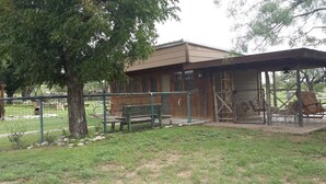 Un bâtiment de style rustique doté d’un espace extérieur clôturé, de bancs et d’un espace de repos abrité.