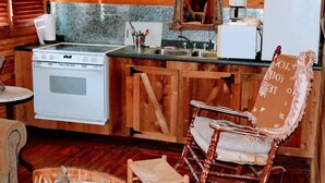 Une cuisine rustique avec un poêle, un évier et des armoires en bois.