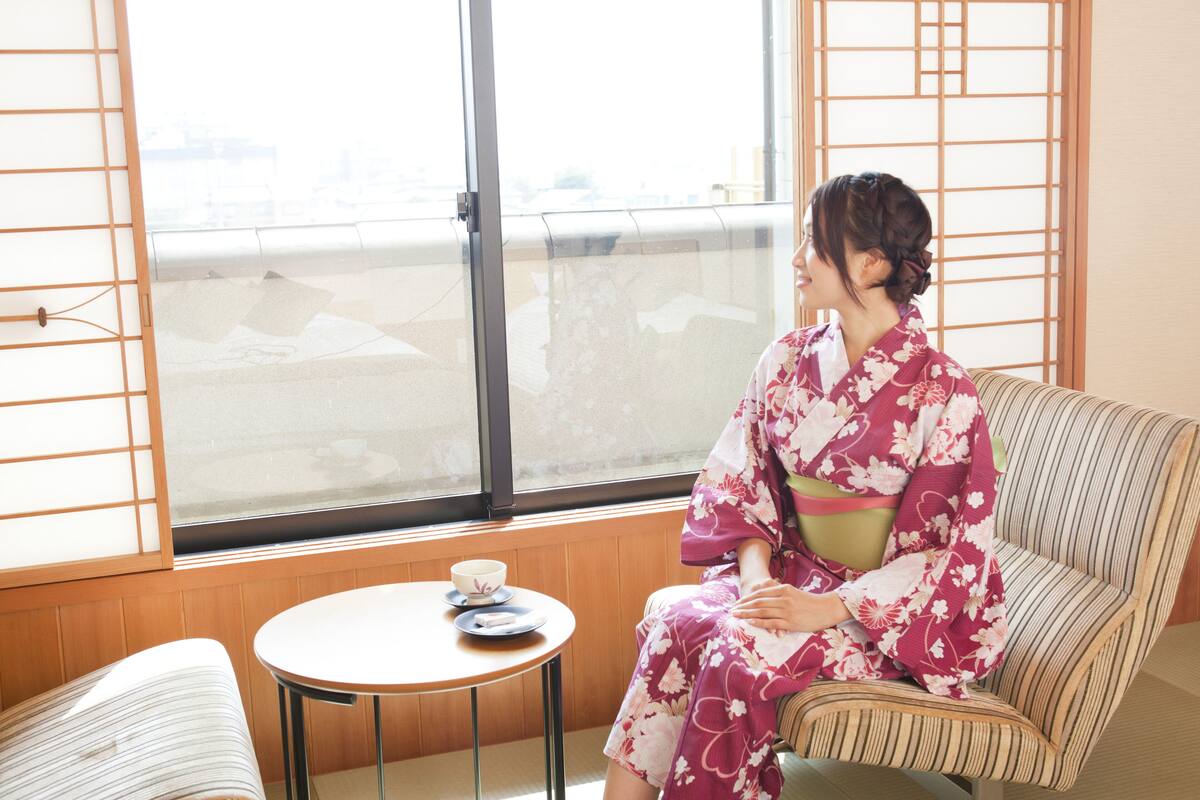 A room with a large window, a round table with a cup and saucer, and a chair.