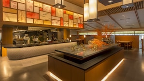 Un intérieur de restaurant moderne avec un îlot central, un bar et des espaces pour s’asseoir.