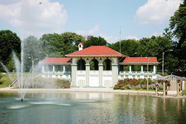 A building with a red roof and columns, a fountain, and a gazebo in front.