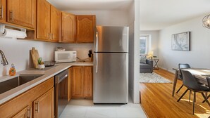 A modern kitchen with wooden cabinets, stainless steel appliances, and a dining area with a table and chairs. -  Pretty  *3BDR/2Bath Home* in a Good Area Next to Parks & Close to Downtown! (St. Louis)