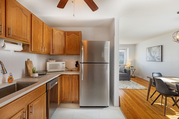 A modern kitchen with wooden cabinets, stainless steel appliances, and a dining area with a table and chairs. -  Pretty  *3BDR/2Bath Home* in a Good Area Next to Parks & Close to Downtown! (St. Louis)