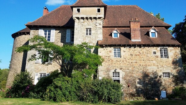 A stone castle with a central tower, multiple windows, and a well-maintained garden. - Authentic 13th century chateau, in 3 acres  surrounded by high stone walls. (Limoges)